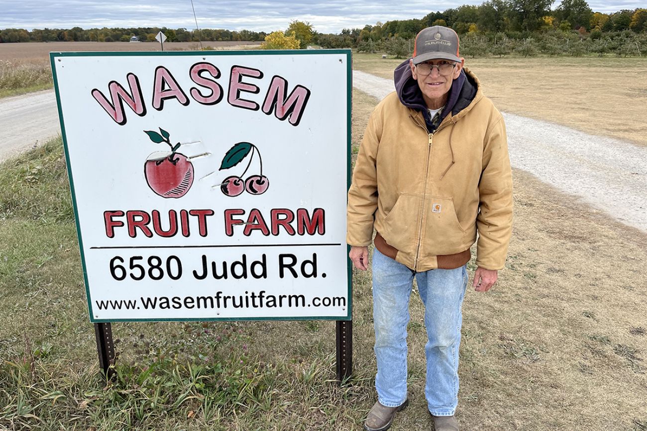 older man by sign on side of the road