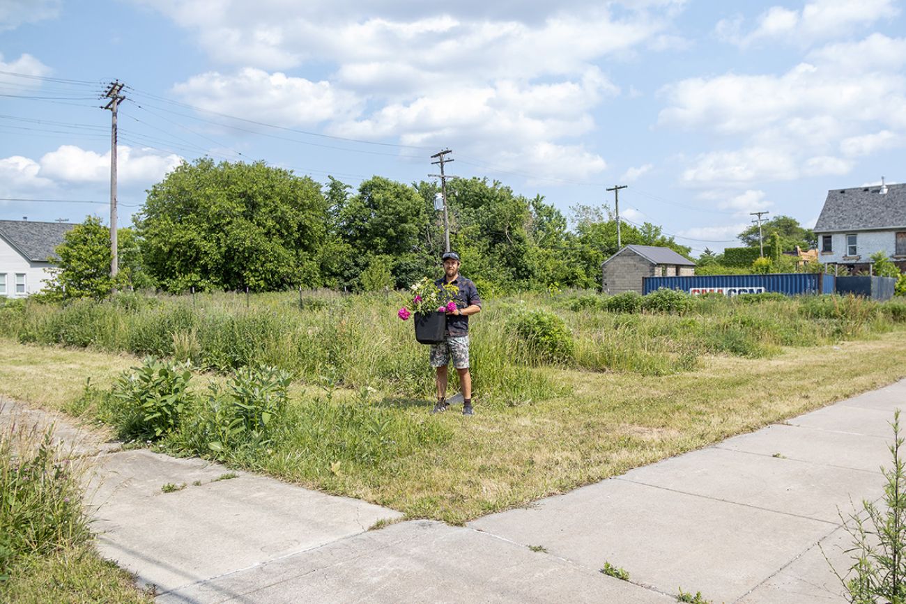 Tim Nutt in a patch of grass holding a pot of flowers