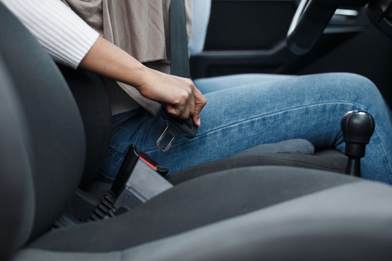 woman driver fastening seat belt in auto