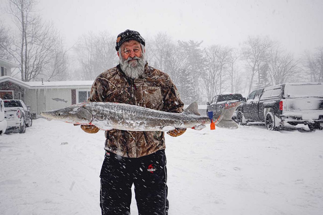 man holding a big fish in the snow