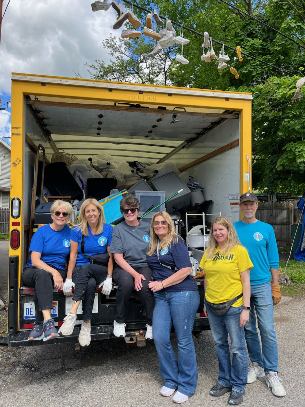 A bunch of people sitting at the back of a moving truck