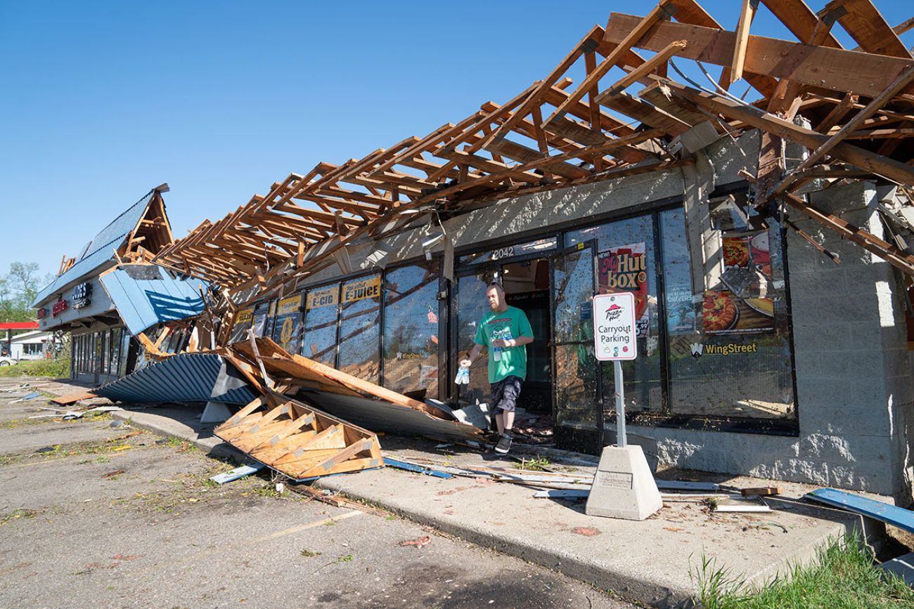 Man walking out of a Pizza Hut in Portage, Michigan. The roof is damaged 