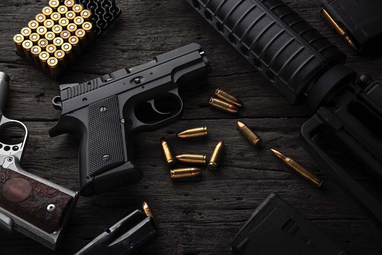 Gun with ammunition on dark wooden background