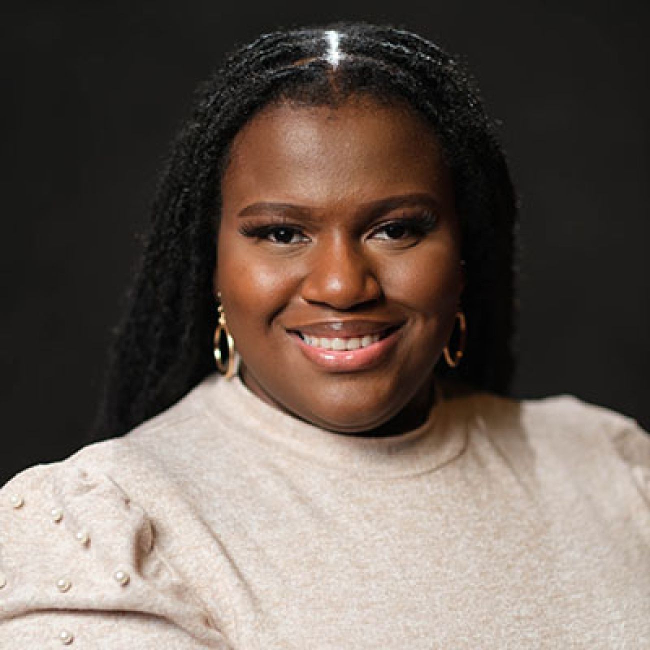 Asha Shaw, headshot. She is wearing a tan sweatshirt