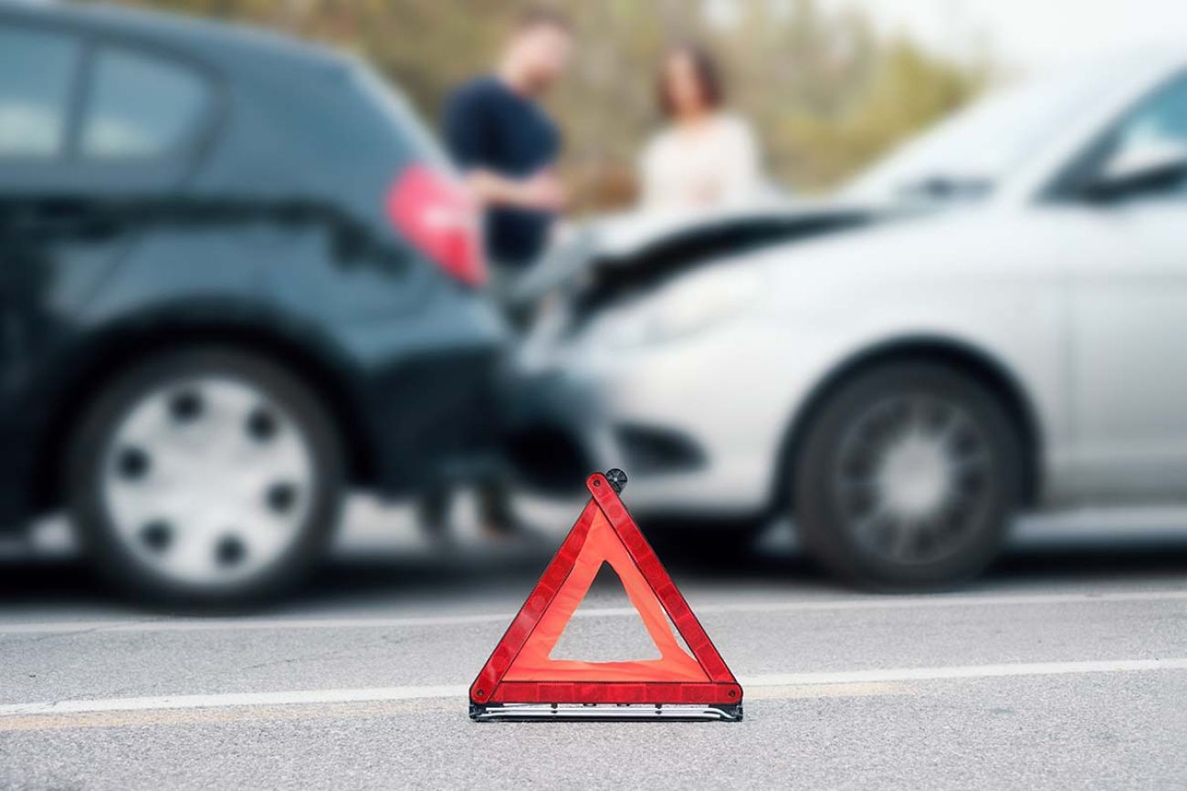 People discussing after a car crash and trying to find an agreement , main focus on the red triangle sign