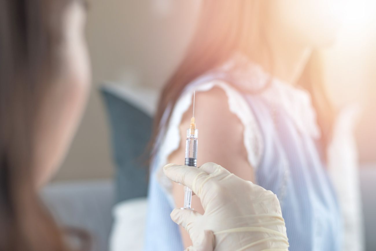 Woman having vaccination with syringe by nurse