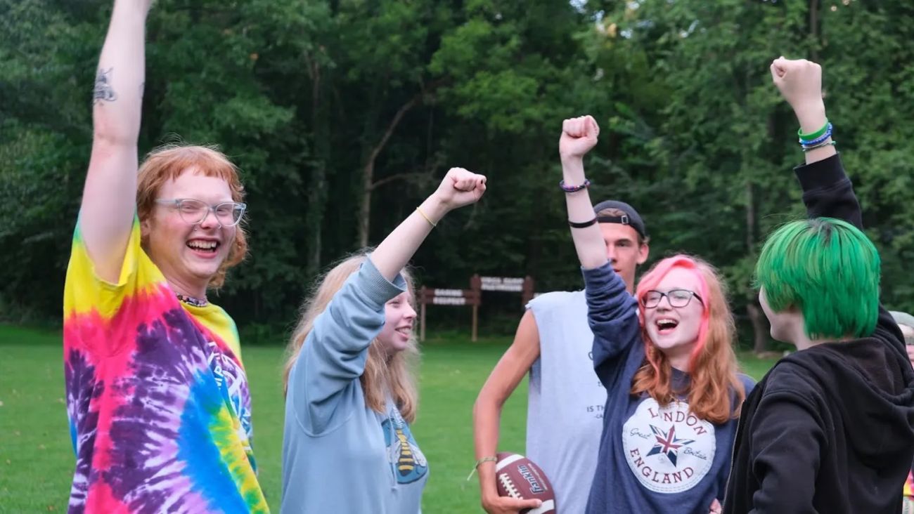 Teenagers outside, putting their hands up