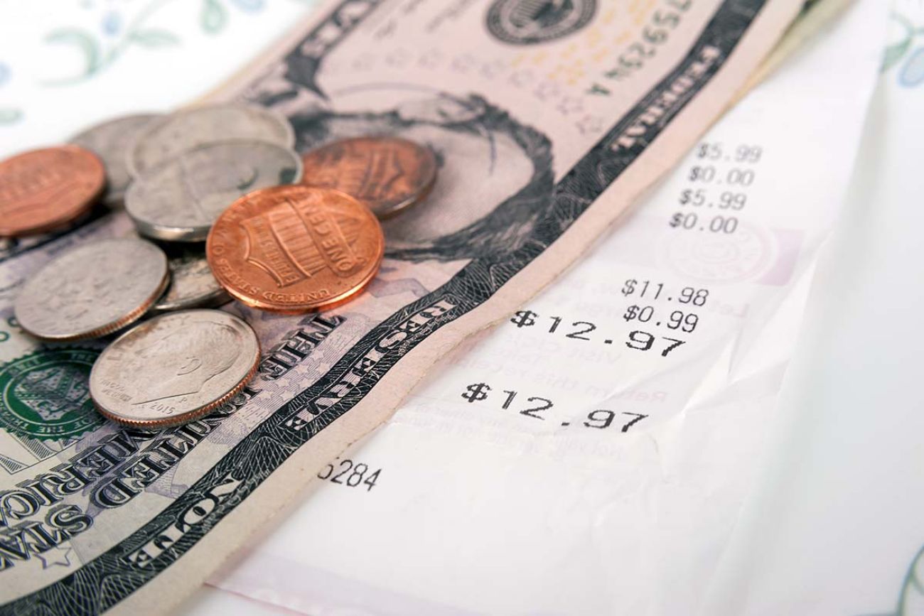 Restaurant bill with dollar bills (tips) on a plate and receipt close up