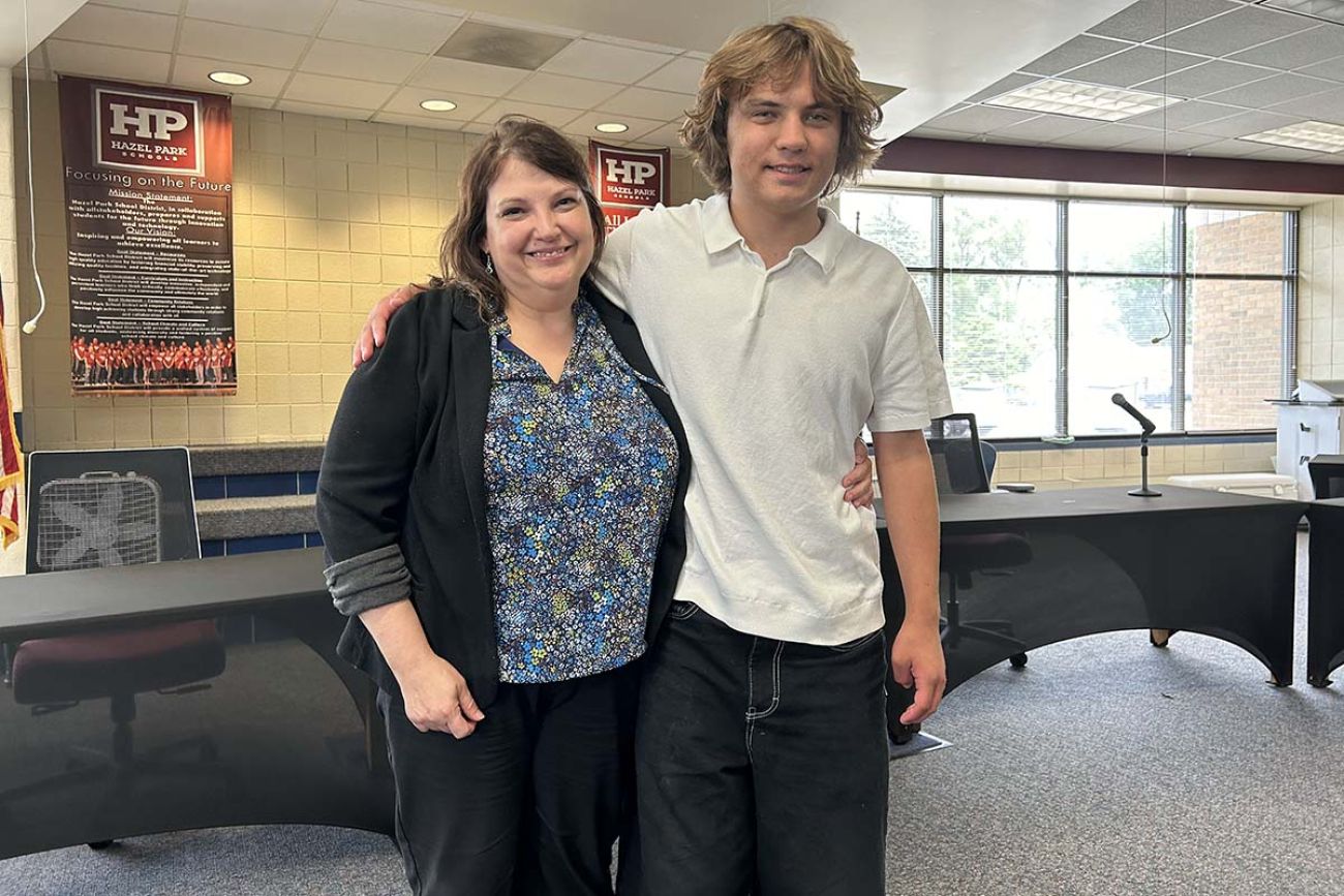 Mother and son posing for a picture together at the school board meeting room