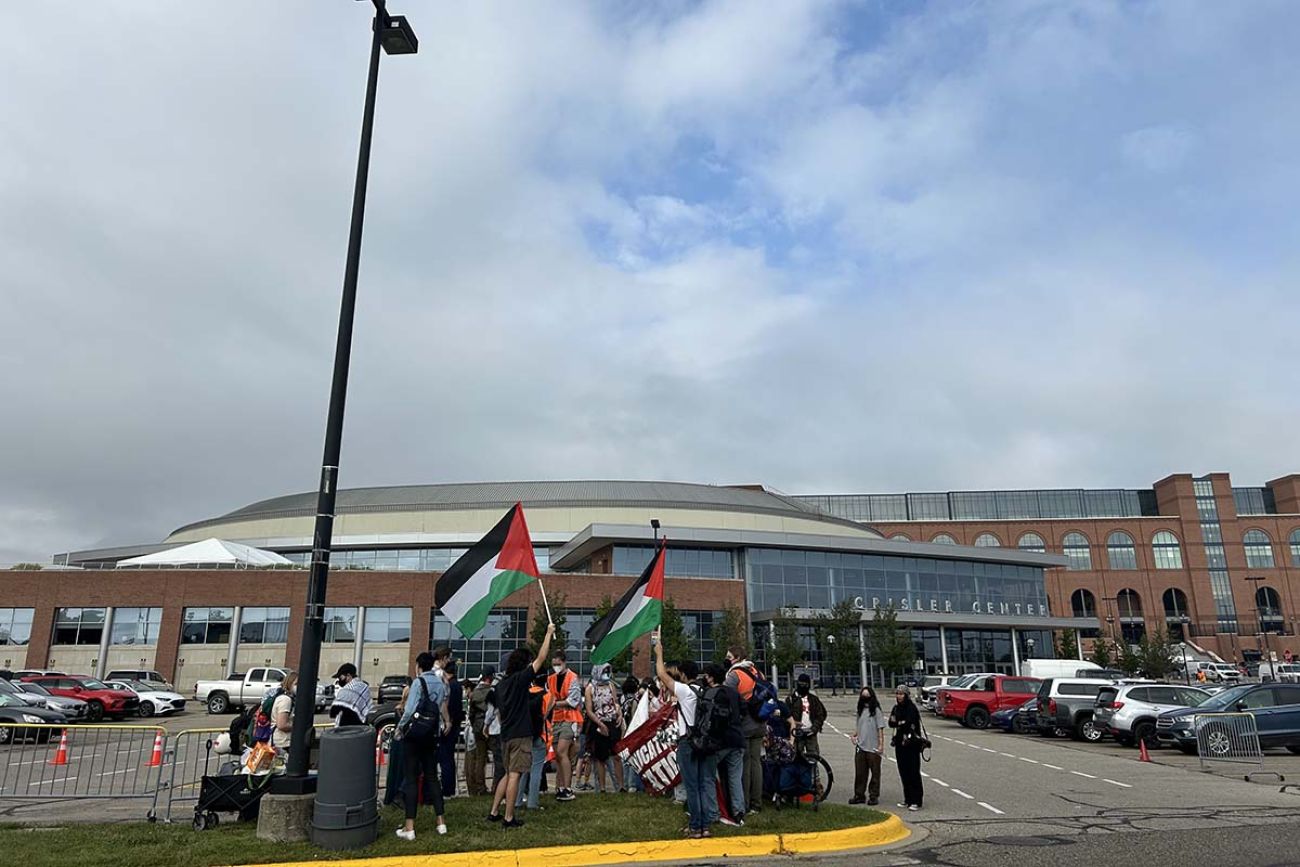 A group of student near a parking lot. Some are carrying Palestine flags