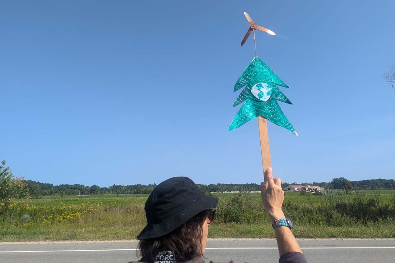 Betsy Moskowitz holding a stick that has paper tree on top