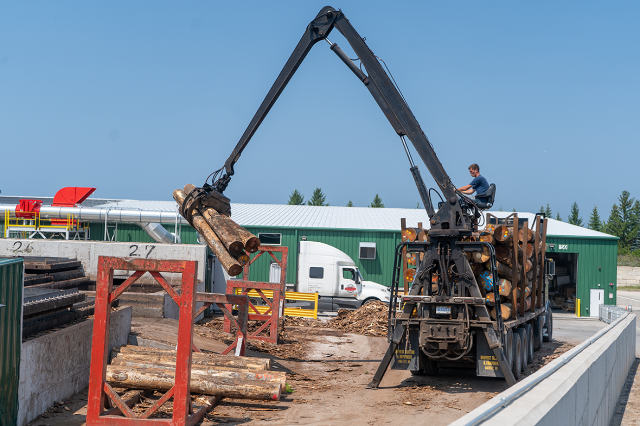 A truck picking up wood from a pile