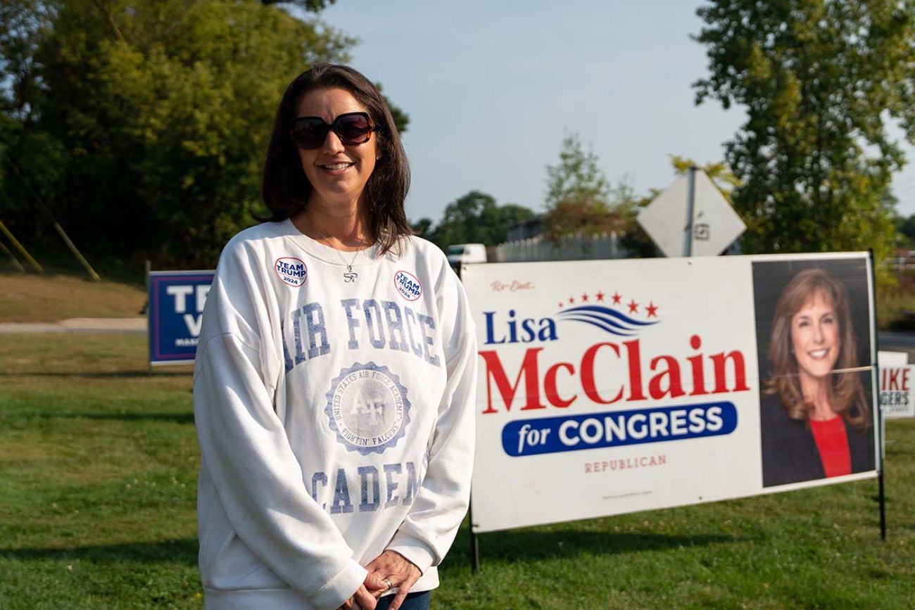 Anna Muzzy, stands next to a Lisa McClain for Congress sign