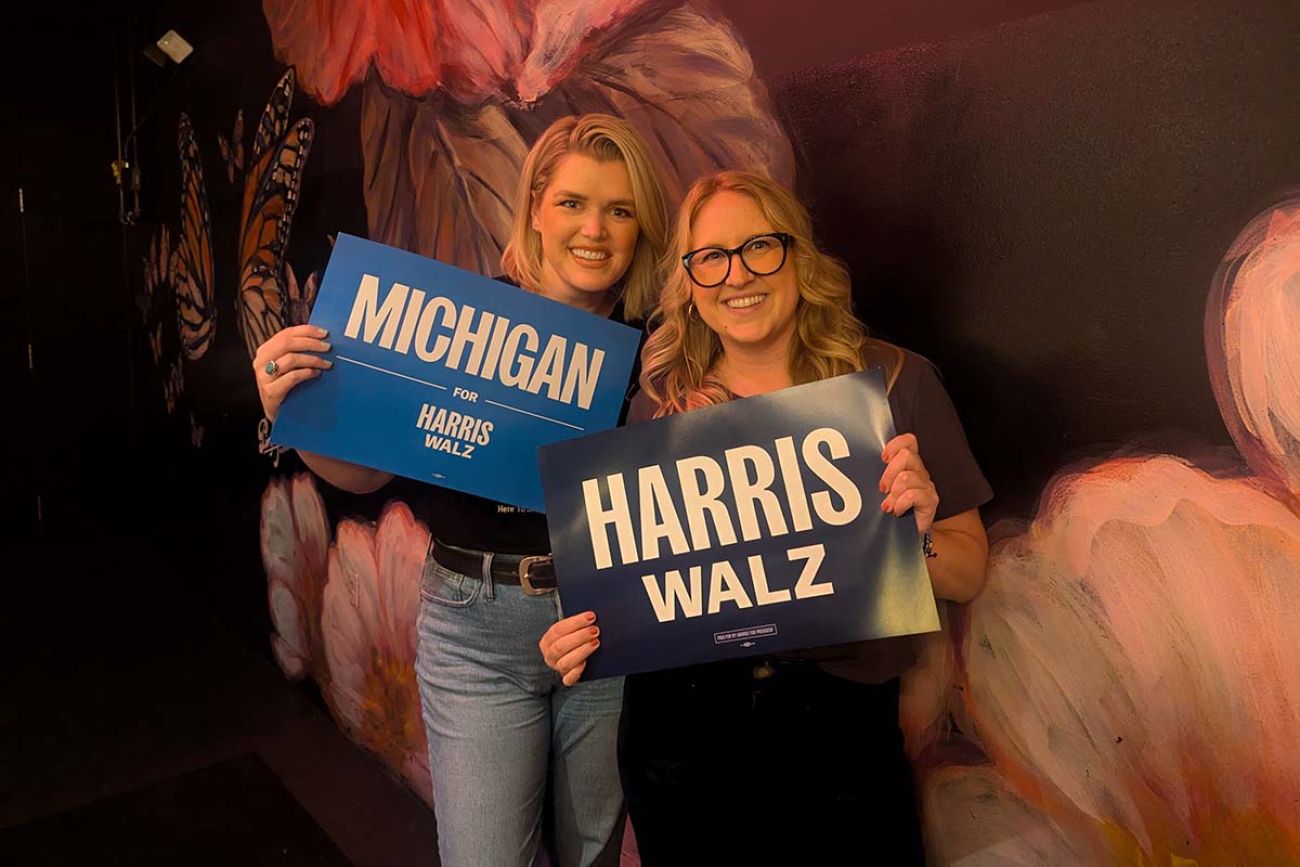 Two women holding up Harris Walz signs