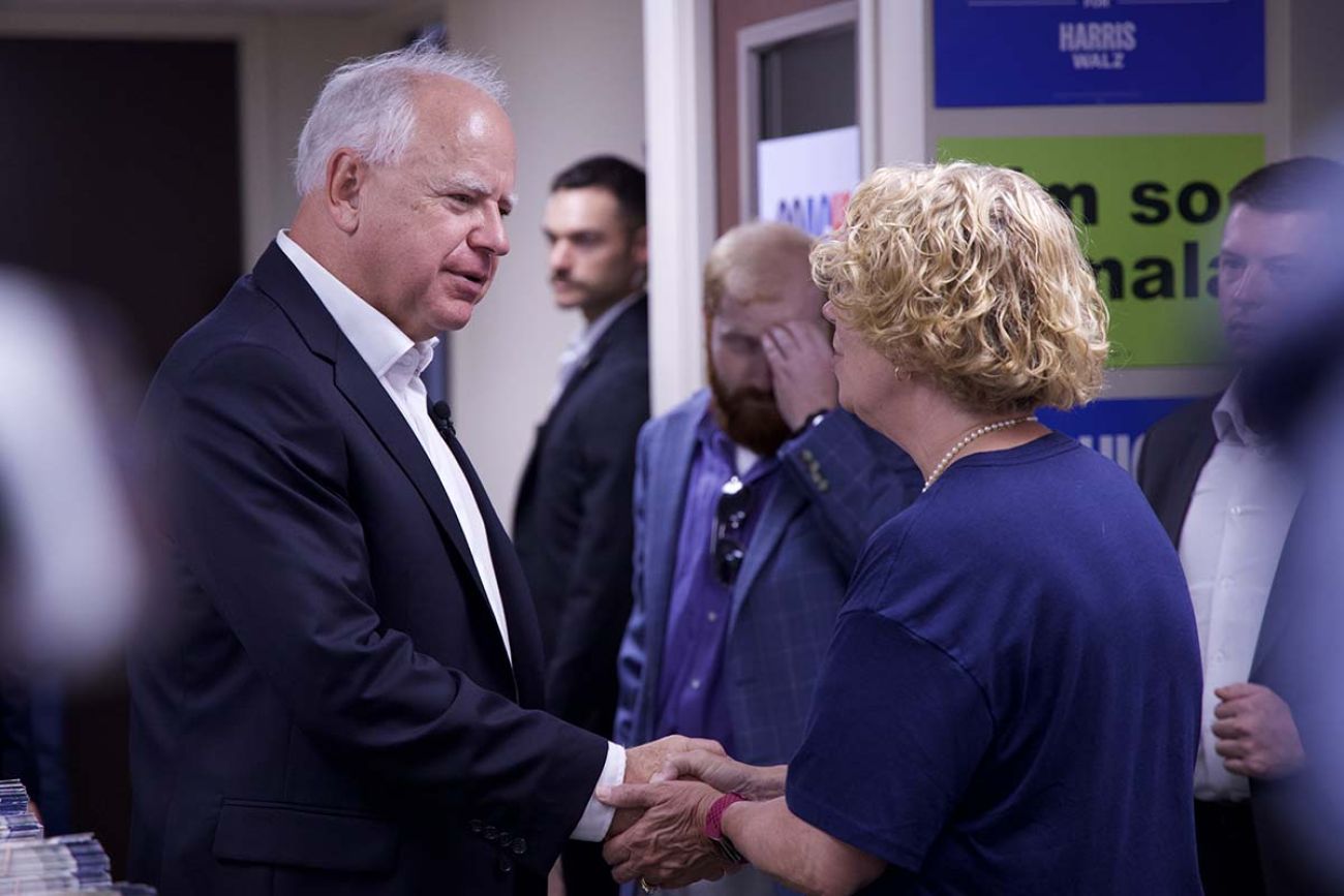 Tim Walz shakes the hand of a woman 