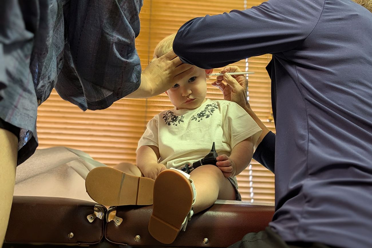 A toddler sits down during Dr. Cheryl Canfield's examination 