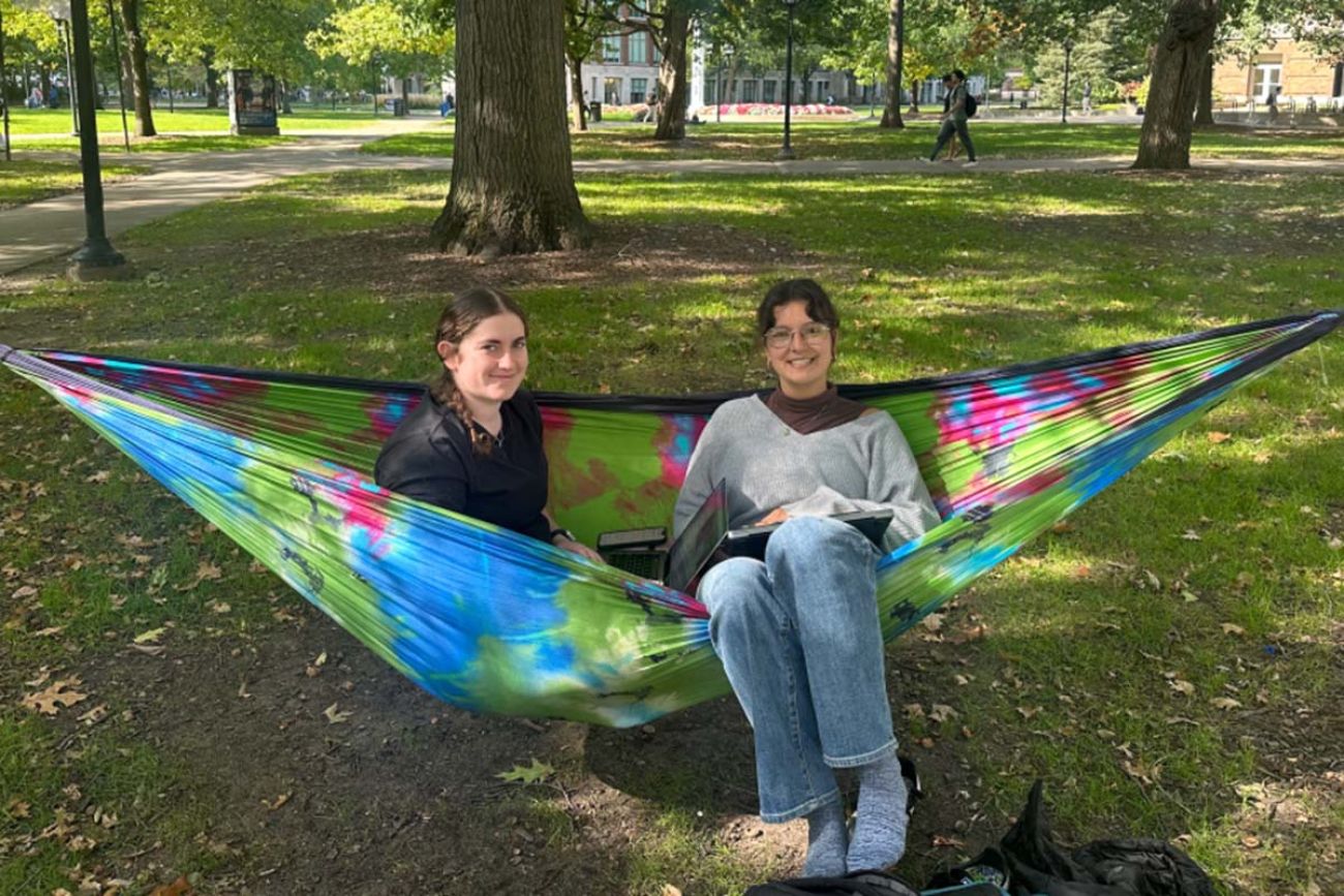 Two college students sitting in the hammock 