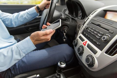 close up of man with smartphone driving car