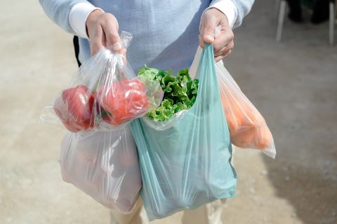 Close up on person buyer hold groceries in bags. 