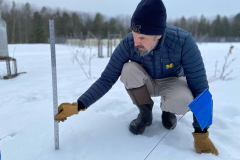 man sticking ruler into snow