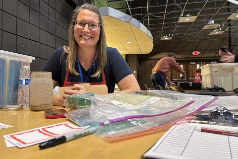 Danielle Bellgowan sitting at a table. The table has name tags and a sign up sheet 