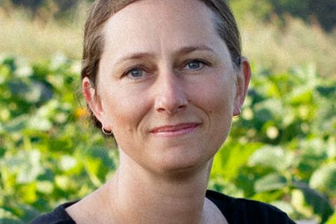 Jen Schaap headshot, with a farm in the background