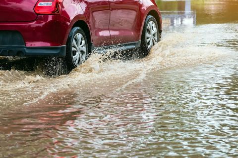 Driving car on flooded road during flood caused by torrential rains.