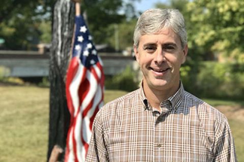 Greg Talberg standing next to an American flag