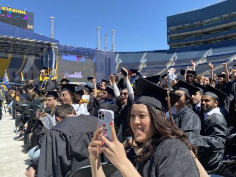 A bunch of students in black graduation room. They are sitting in seats