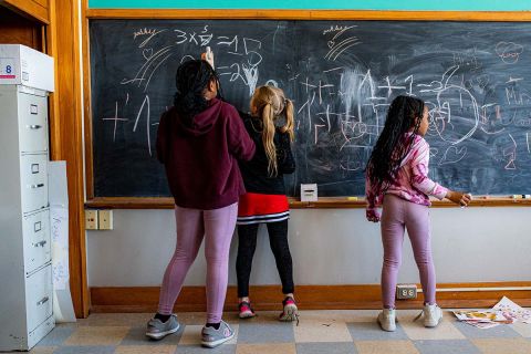 Kids writing on a chalkboard at school