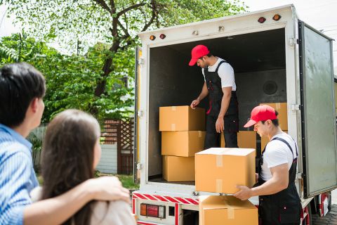 workers in uniform unloading cardboard boxes from the truck. Delivery men unloading boxes