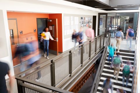 Busy high school corridor with blurred students and staff