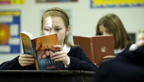 Students reading books at their desks in a classroom