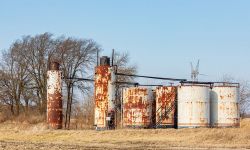 Old oil well storage tanks in farm field.