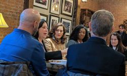 whitmer sitting at a table with other people