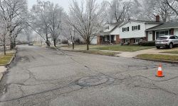 A wire down on the street. nearby trees covered by ice