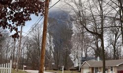 The rising smoke cloud after authorities released chemicals from a train derailment as seen from the ground in a nearby neighborhood.