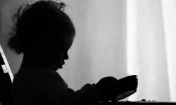 A two year old girl is sadly looking into her empty bowl wishing she had more to eat. 