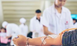 Nurse preparing to get blood from donors at blood donations center, selective focus on man's forearm