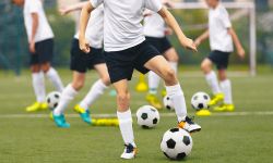 Group of teenage boys kicking soccer balls during a training session. 