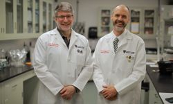 Two men stand side by side in a lab