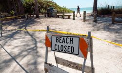 A barricade with sign is posted on Bradenton Beach Florida to warn beaches are closed for public safety during covid coronavirus pandemic