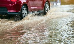 Driving car on flooded road during flood caused by torrential rains.