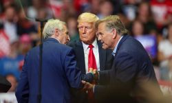 Business executive and former U.S. Senate candidate Sandy Pensler shakes hands with Republican front-runner Mike Rogers on stage. Supporters behind him