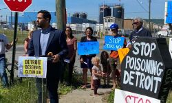  State Rep. Abraham Aiyash (D-Hamtramck) speaks at a protest at the US Ecology hazardous waste facility in Detroit. People are standing behind. They are on a street corner