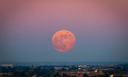 The strawberry Supermoon at sunset gradient from blue to pink on the city skyline in June 2020 in Spain.