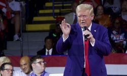 Donald Trump, wearing a blue suit, talking into a microphone