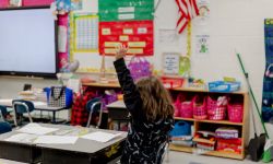 A child raising their hand in a classroom