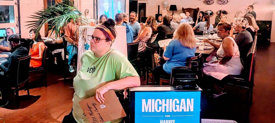 Pleasant Ridge resident Jordan Weisman stands next to a Michigan Harris-Walz sign in a roonm