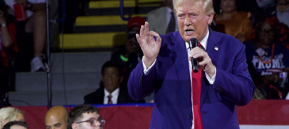 Donald Trump, wearing a blue suit, talking into a microphone